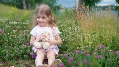 一个小女孩和一只玩具兔子在草地上的四叶草中玩耍